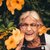 Roberta Johnson smiling with eyes closed near a plant with orange flowers
