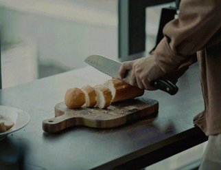 Close-up short looping video of someone slicing a baguette on a bread board